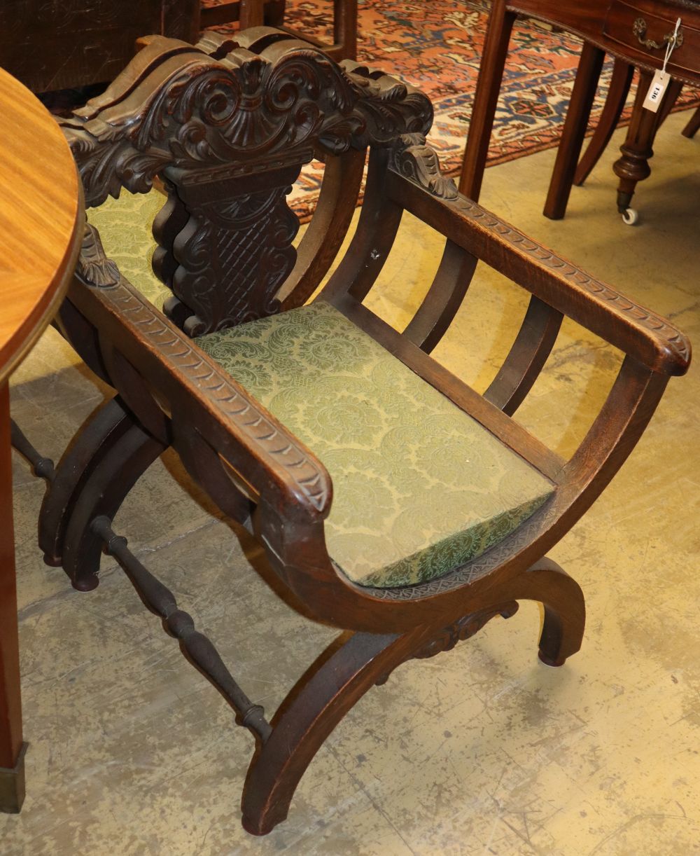 A set of four early 20th century carved oak X-frame chairs, W.61cm, D.58cm, H.76cm